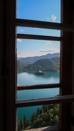 Panoramic view to the lake Bled and surrounding mountains through a windowの写真素材