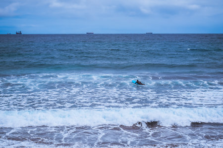 Surfer on the board and ships in the distanceの写真素材