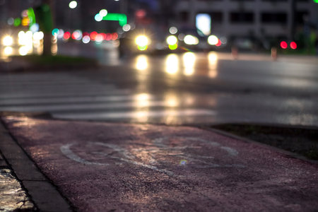 Bike sign on the sidewalk with red background and car lightsの写真素材