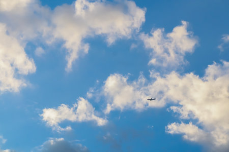Blue sky with clouds and airplane during a sunny dayの写真素材