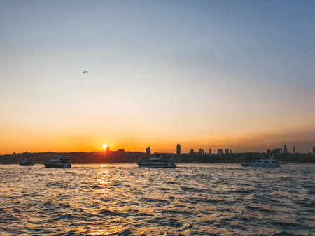View of Bosphorus with cruise ships and Istanbul city during the sunset with the sun reflecting in the waterの写真素材