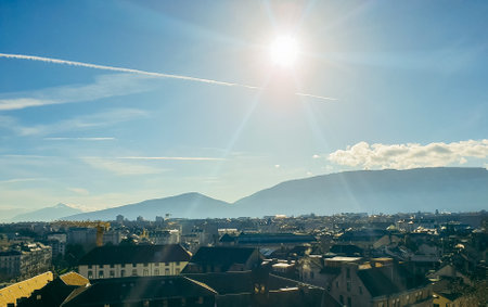A breathtaking aerial view of Geneva, Switzerland, showcasing its historic rooftops, modern skyline, and stunning mountain backdropの写真素材