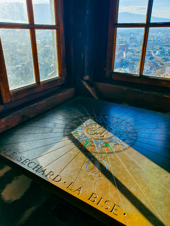 A beautifully crafted sundial inside a historic tower in Geneva, Switzerland, with a stunning city view through wooden windowsの写真素材