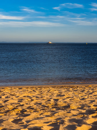 A serene beach in Portugal with golden sand, calm ocean waters under a vibrant blue skyの写真素材