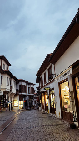 21st of December 2024, Ankara, Turkiye - Traditional Ottoman-style houses line a cobblestone street with glowing storefronts under a twilight sky in Ankaraのeditorial素材