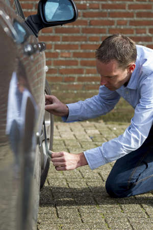 Mid adult man using duct tape to fix his car  Vertical shot の写真素材