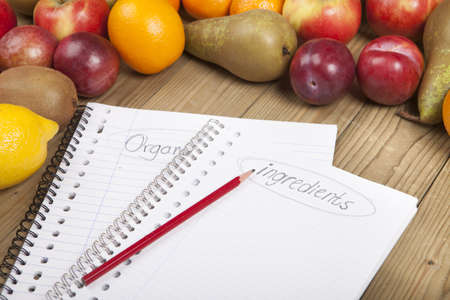 Pencil on spiral books with fruits in the background on wooden surfaceの写真素材