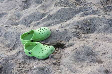 Sandals sitting alone on the sandy beach.
