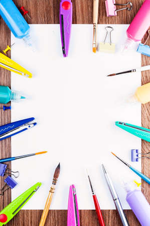 White sheet of paper spread out around the brushes, scissors, paints and small detailsの写真素材