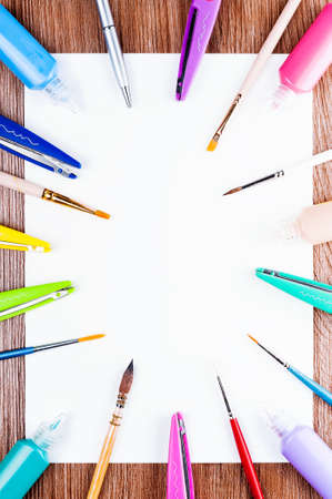 White sheet of paper spread out around the brushes, scissors and paintsの写真素材