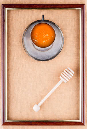 Portrait of honey in an iron cup and saucer with honey dipperの写真素材