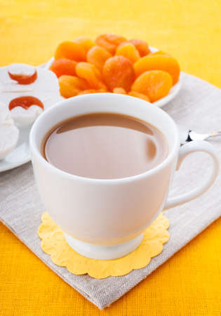 White cup of coffee with breakfast items on the orange textured linen napkinの写真素材