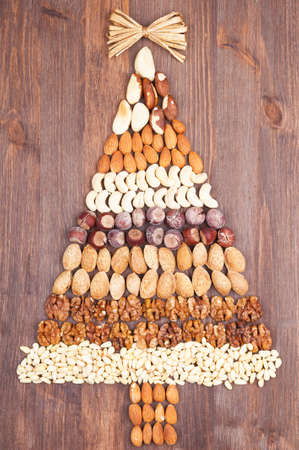 Set of different varieties of nuts in the form of a tree with a gold bow at the topの写真素材