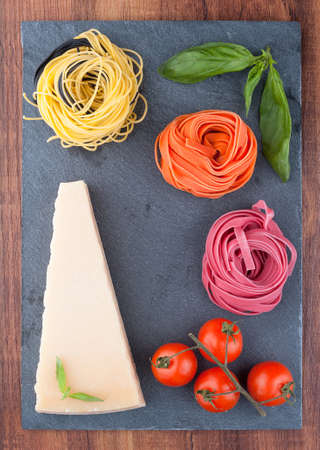 Colored Italian pasta on a black textured boardの写真素材
