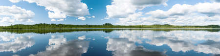 Panorama of the northern lake with blue sky and clouds
