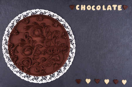 Round Chocolate cake on a slate board top view. Chocolate chocolate letters with text chocolate and...
