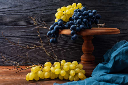 Still life with blue and green grapes on a background of black textured wood in a rustic style with copy spaceの写真素材
