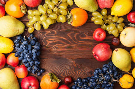 Frame autumn fruits on a wooden board top view with copy spaceの写真素材