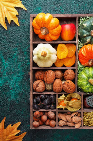 Set of autumn vegetables, fruits, nuts and seeds in a wooden box with cells top view with copy spaceの写真素材