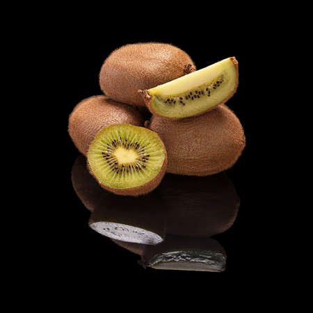 Bunch of whole kiwi fruit and in a cut isolated on black glossy background with real reflection.の写真素材