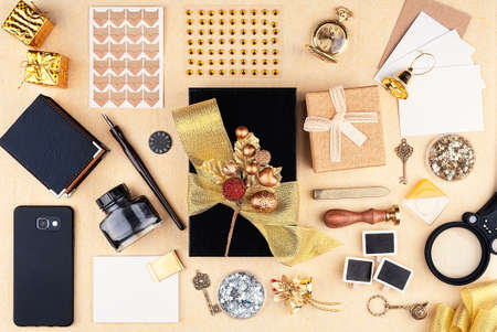 Gift wrap in the workplace. Top view. Black box with a gold bow and big group of toolの写真素材