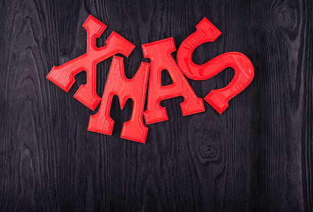 Composition of red wooden letters word Xmas on black textured wooden top view with copy spaceの写真素材