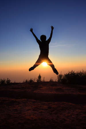Silhouette man  jumping over the sunの写真素材