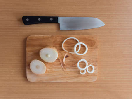 Onion and onion rings on chopped board with knife