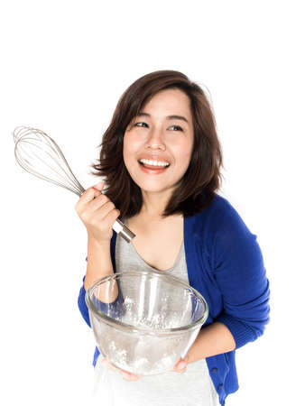 Isolated portrait of beautiful young success woman with whisk and flavour bowl on white background. Pretty female multi-racial Asian Caucasian model smiling happy.の写真素材
