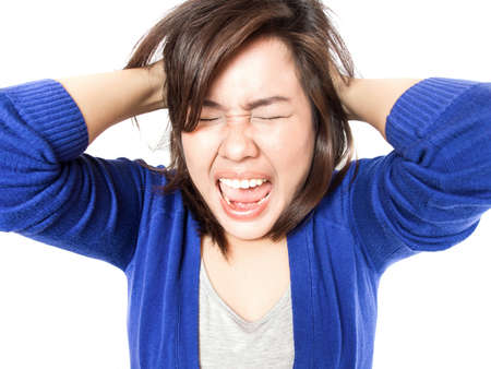 Isolated portrait of young stress woman going crazy pulling her hair in frustration on white background. Pretty female model angry.の写真素材