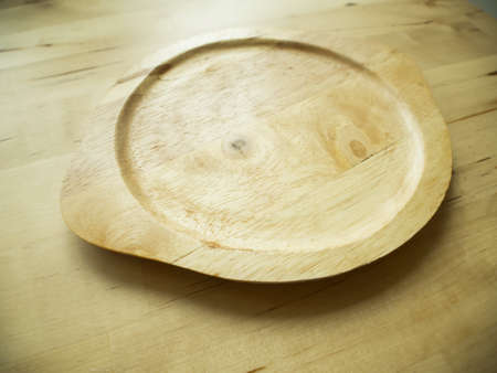 Empty wooden plate on the brown wooden table background