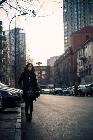 Urban modern woman walking in city street.Vintage retro effect filtered hipster style image.の写真素材