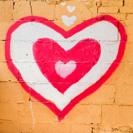 Red hearts painted on brick wall.の写真素材