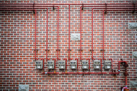 Row of residential natural gas meters and pipe on brick wallの写真素材
