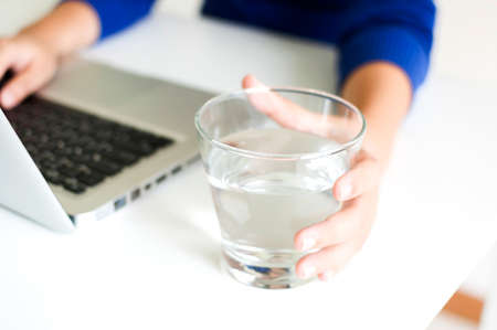 Drinking water while working with laptop computerの写真素材