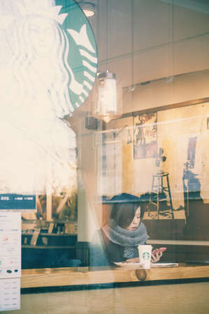 Seoul, South Korea - March 04, 2015: Customer with breakfast coffee and looking at smartphone at Starbucks cafe. Starbucks Corporation is global coffee company chain based in Seattle, Washingtonのeditorial素材