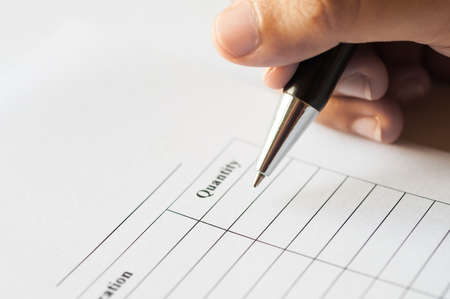 Female hands with pen writing on paper with quantity table list.の写真素材