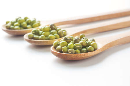 Green mung beans in wood spoon on white background.の写真素材