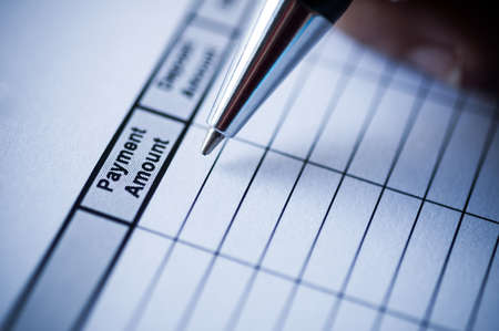 Female hands with pen writing on paper with table of payment amount.の写真素材