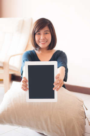 Young asian woman holding blank digital tablet, Focused on the tablet.の写真素材