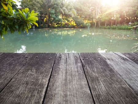 Old wood dock with garden pond on background.の写真素材