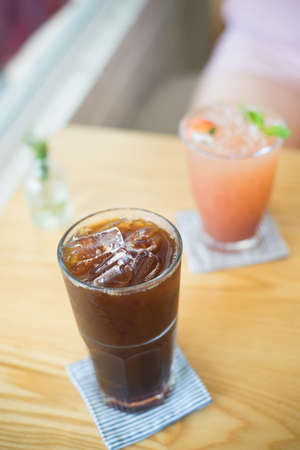 Ice coffee and fresh juice in cafe, shallow depth focus.