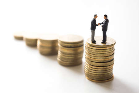 Businessmen checking hand over coins stacks. Investment concept.の写真素材