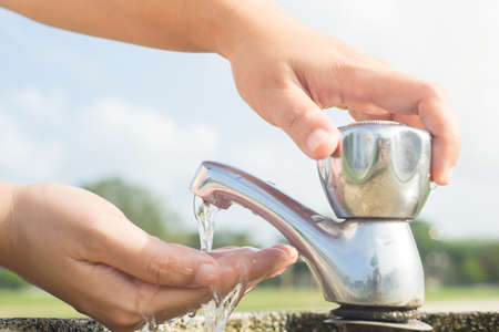 Washing hands at outdoor faucet.の写真素材