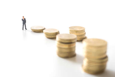 Businessman thinking in front of coins stacks. Investment concept.