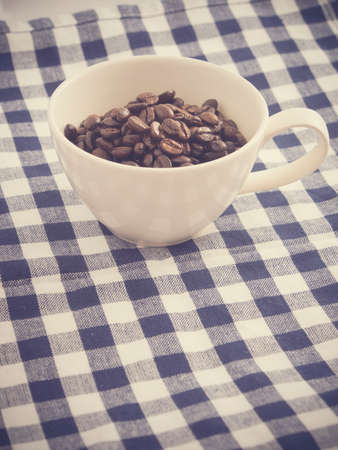Cup full of coffee beans on the clothの写真素材