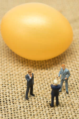 Financial investment concept. Businessmen talking in front of golden egg.の写真素材