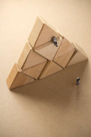 Concept of business learning success. Businessman sitting on top of triagle wood block.の写真素材