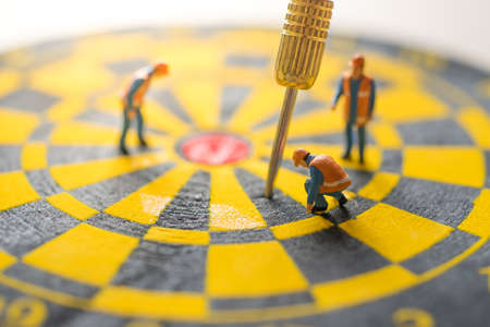 Concept of missed target business strategy. Worker diagnosis the untargeted arrow on dart board.