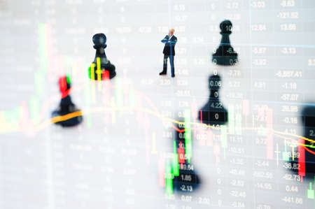 Concept of stock market strategy. Stock market number on screen display with businessman and chess gameの写真素材